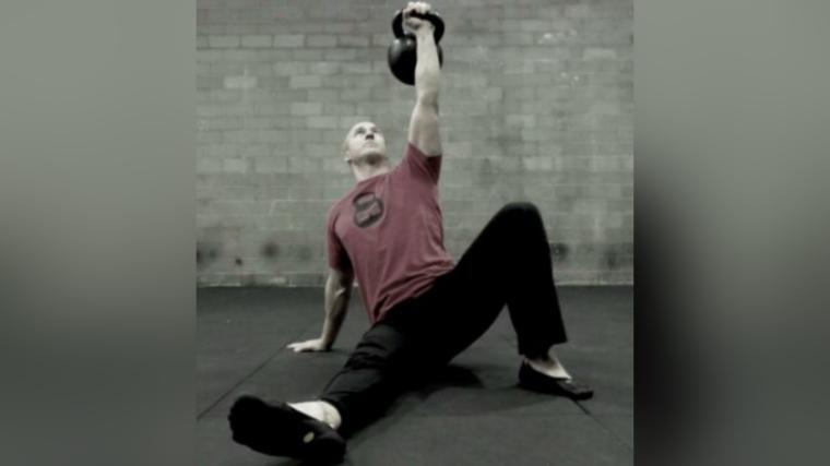 Man gripping a kettlebell in a Turkish Get-Up position