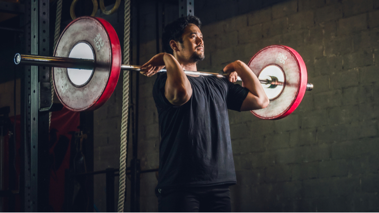 man holding barbell in front of shoulders ready to exercise
