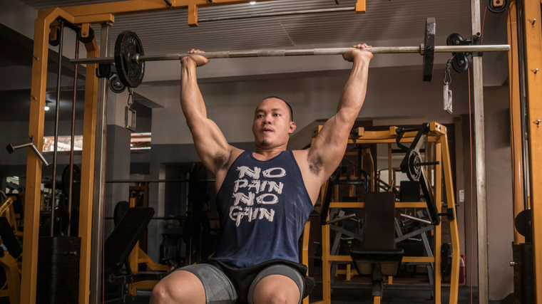 Man in gym performing barbell shoulder press