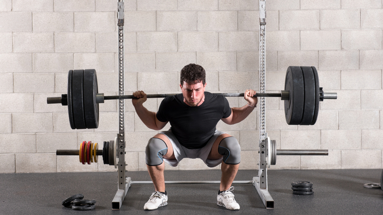 Man in gym performing squats with barbell